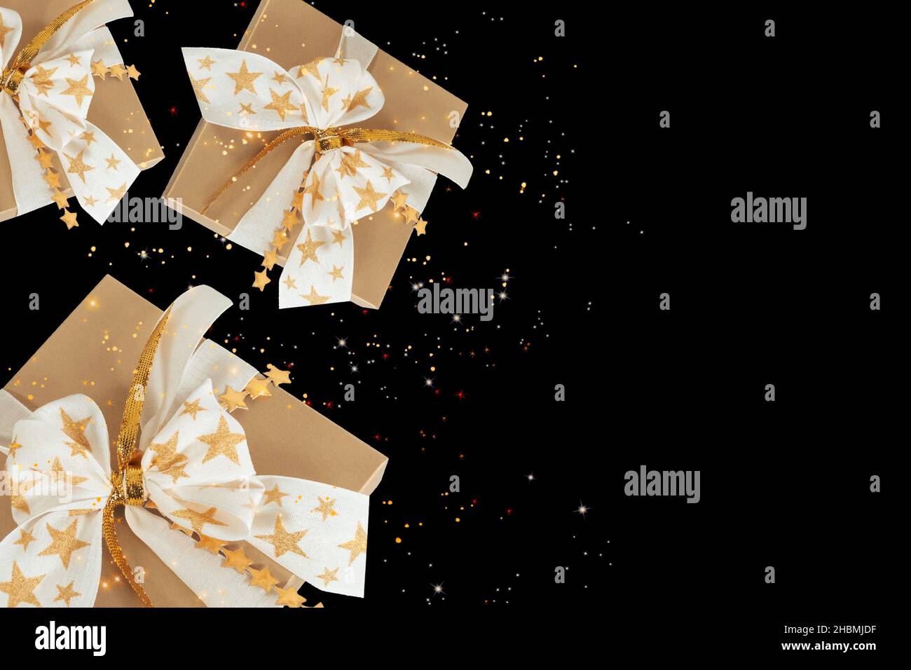 Scatole regalo in oro volante con stelle scintillanti su sfondo scuro. Foto Stock