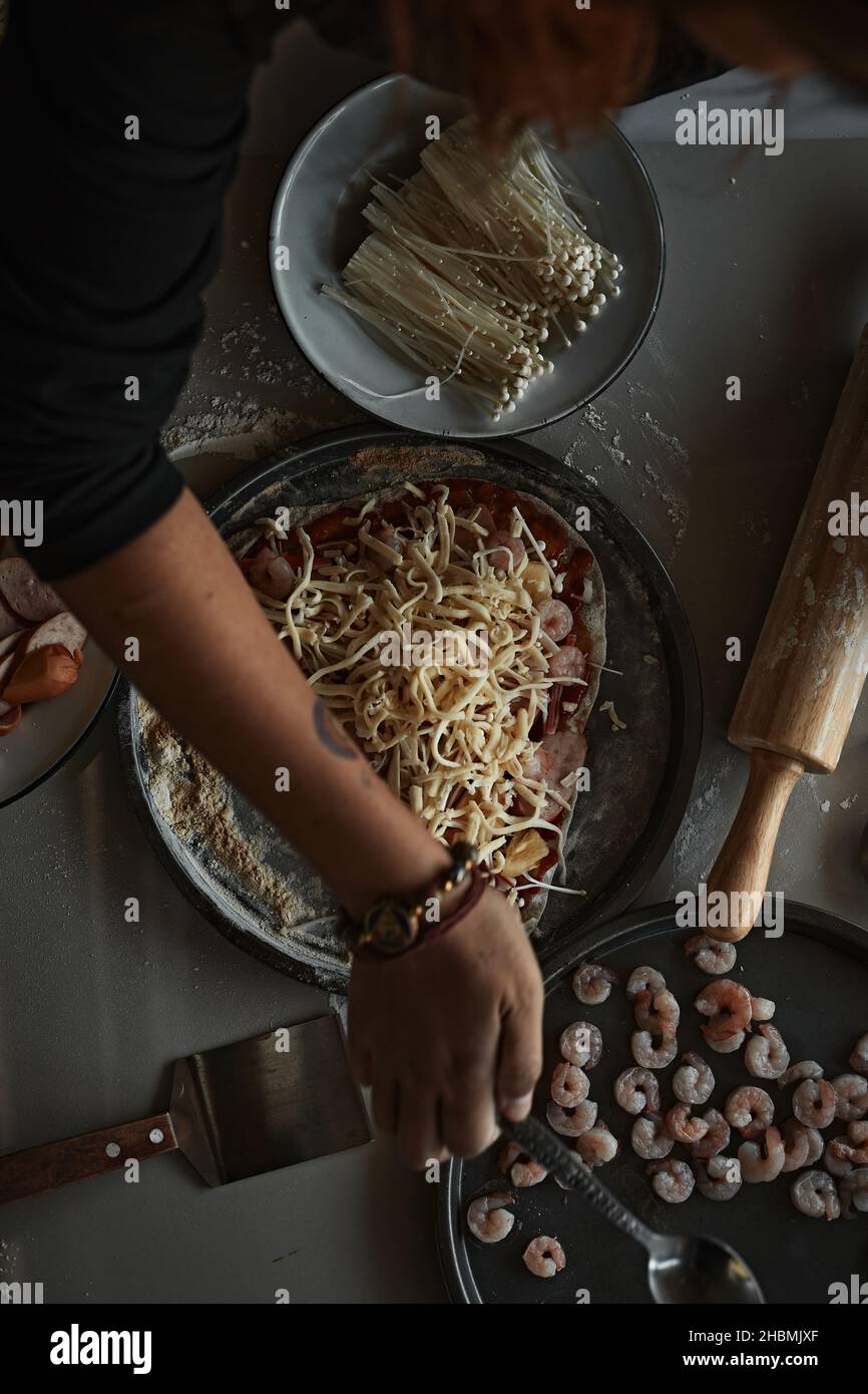 Un primo piano di preparazione di una pizza italiana su una superficie infarinata. Foto Stock