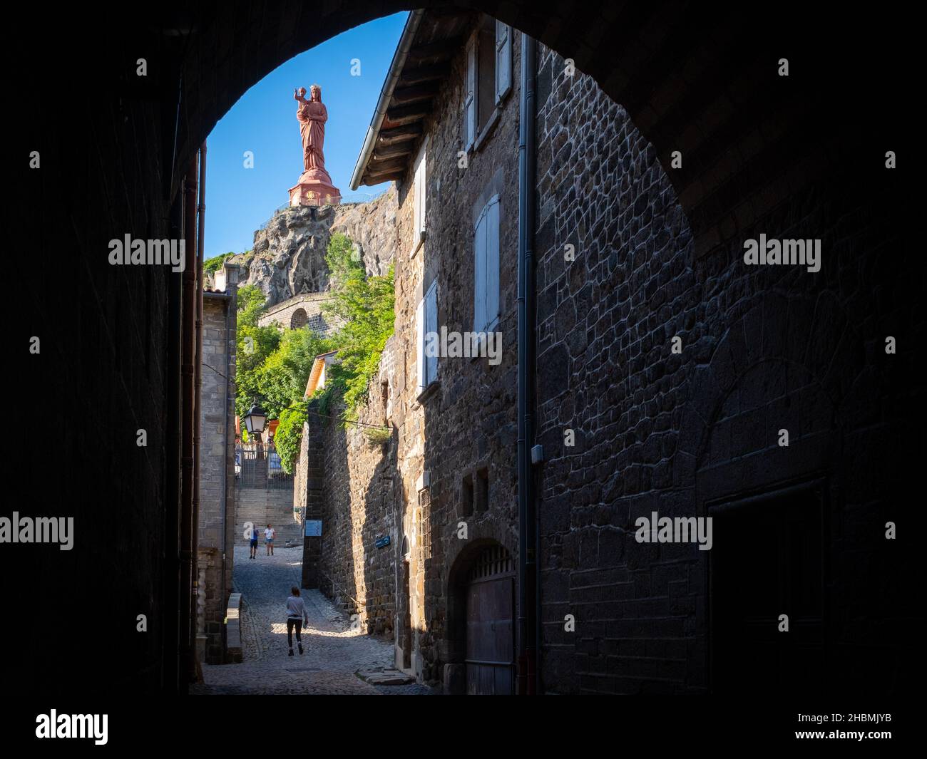 Le Puy-en-Velay, Francia - 9 luglio 2021: Una scultura molto alta della Vergine Maria vista da una strada stretta nella città vecchia di le Puy-en-Velay con pochi Foto Stock