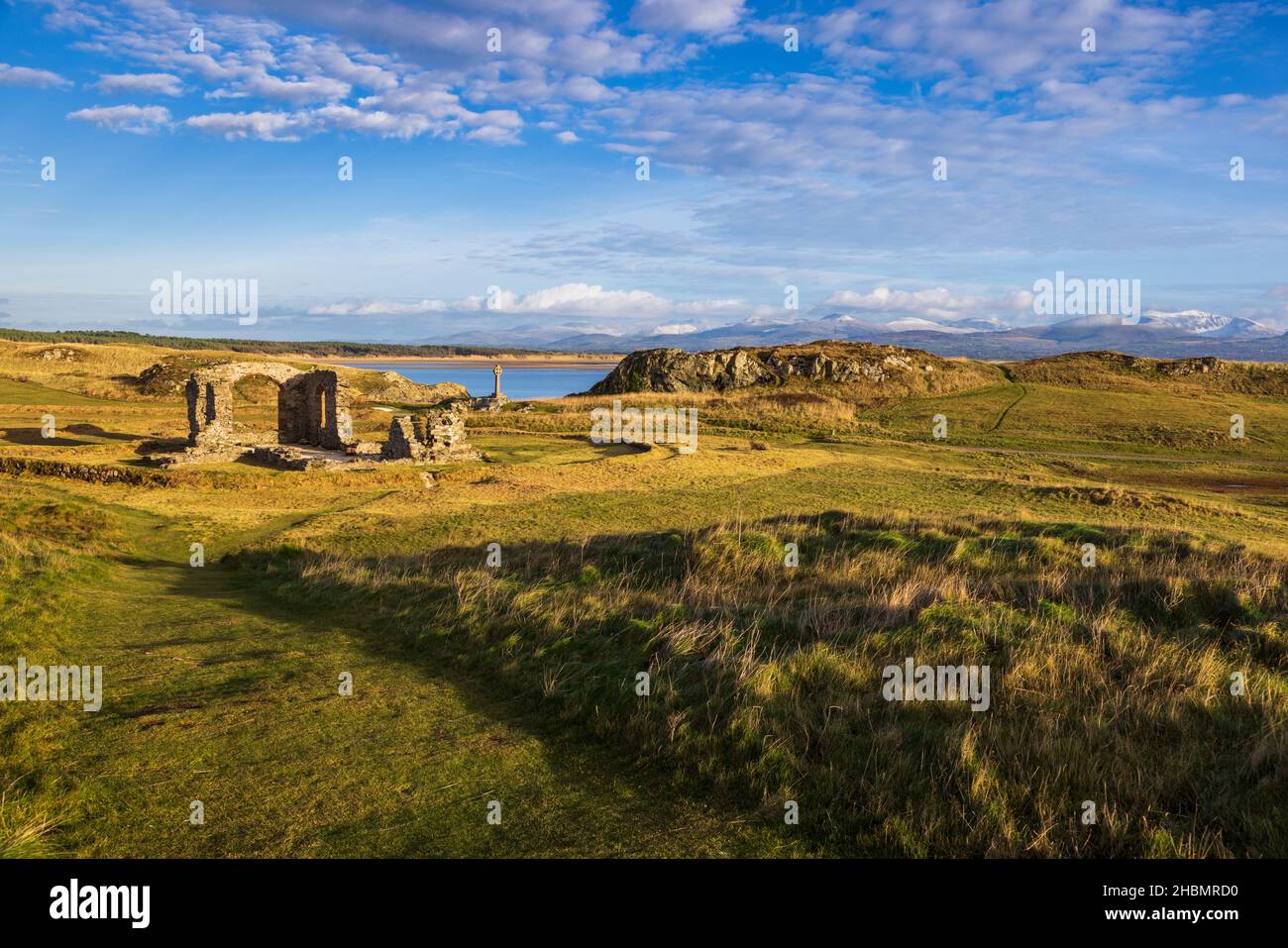 La croce celtica e le rovine della chiesa di San Dwynwen sull'isola di Llanddwyn, Isola di Anglesey, Galles del Nord Foto Stock