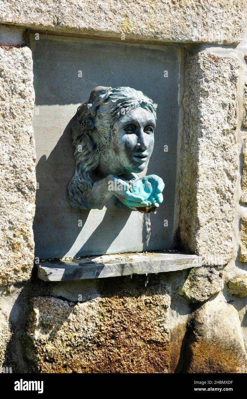 Faccia e le mani a tazza l'acqua caratteristica in una nicchia di pietra di granito a Abbey Gardens Tresco, Isole di Scilly, Cornovaglia Foto Stock
