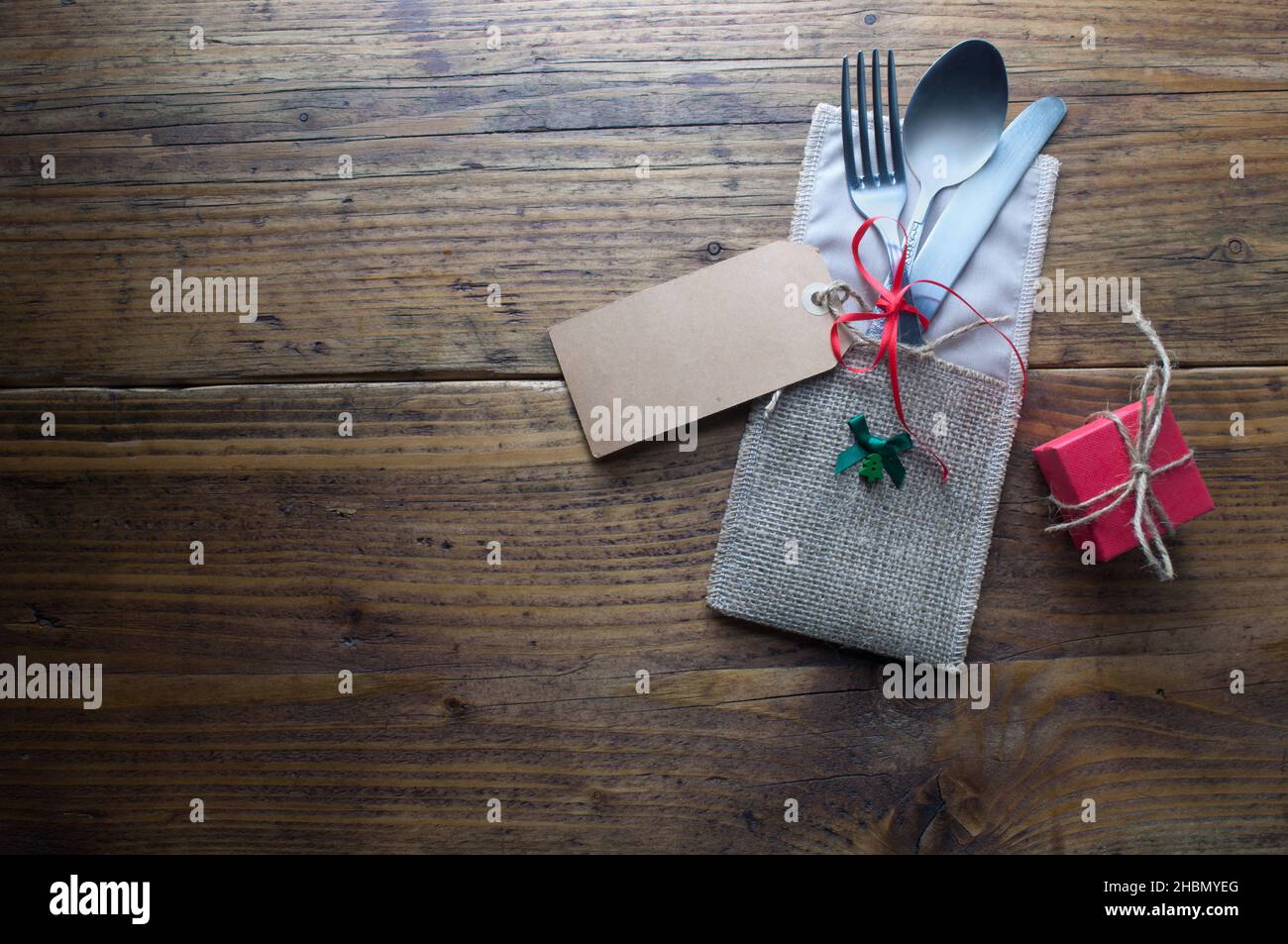 Tavolo pranzo festivo, biglietto d'auguri attaccato alla forchetta e coltello su tavolo di legno Foto Stock