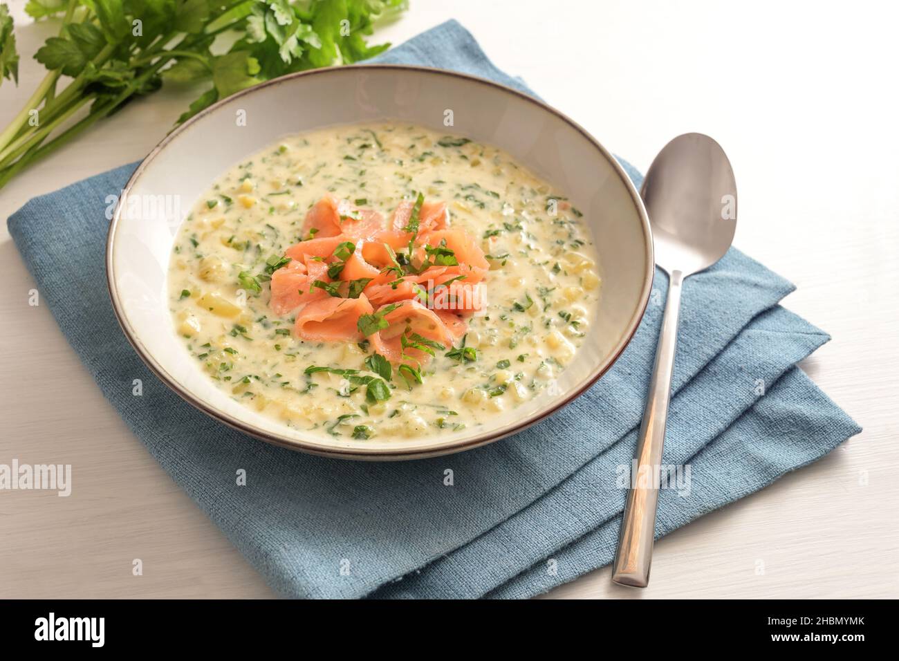 Zuppa di verdure di prezzemolo e patate con strisce di salmone su un tovagliolo blu e una tavola bianca, fuoco selezionato, profondità di campo stretta Foto Stock