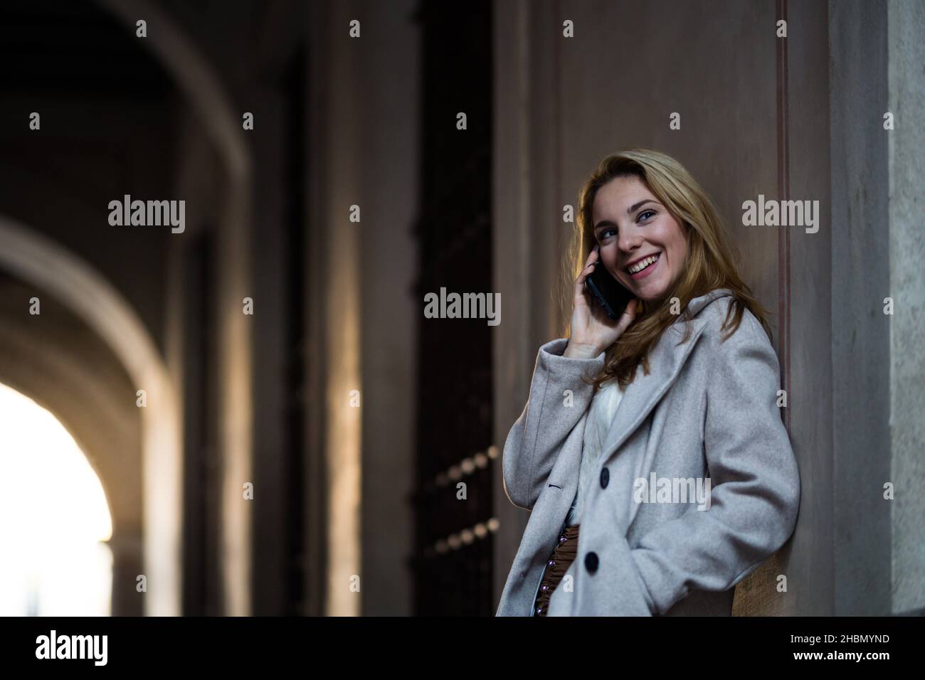 ragazza sorridente che parla con il suo smartphone per strada Foto Stock