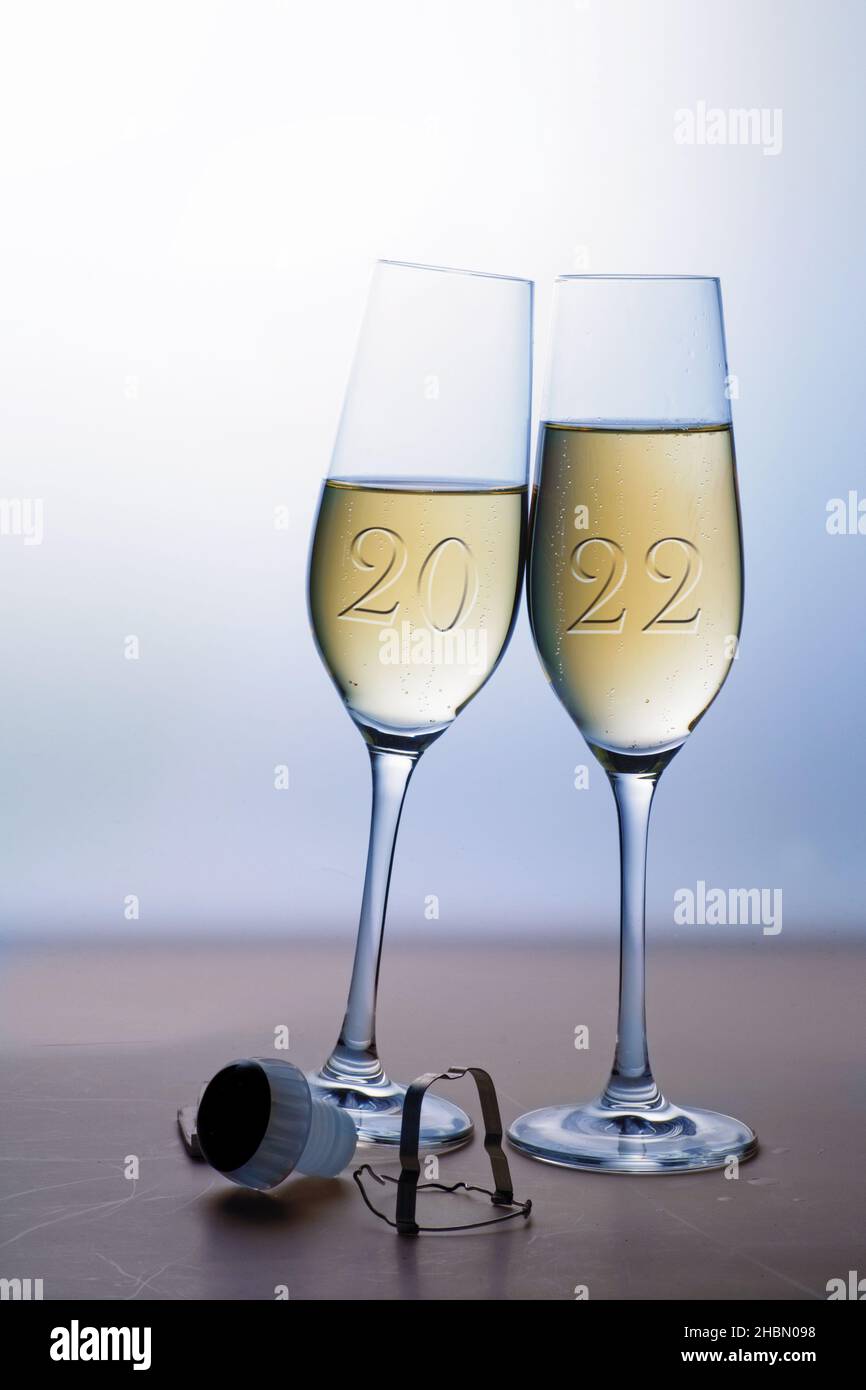 Due bicchieri da champagne con tostatura di Capodanno 2022, concetto di amore e vacanza, sfondo grigio blu con spazio copia, focus selezionato Foto Stock