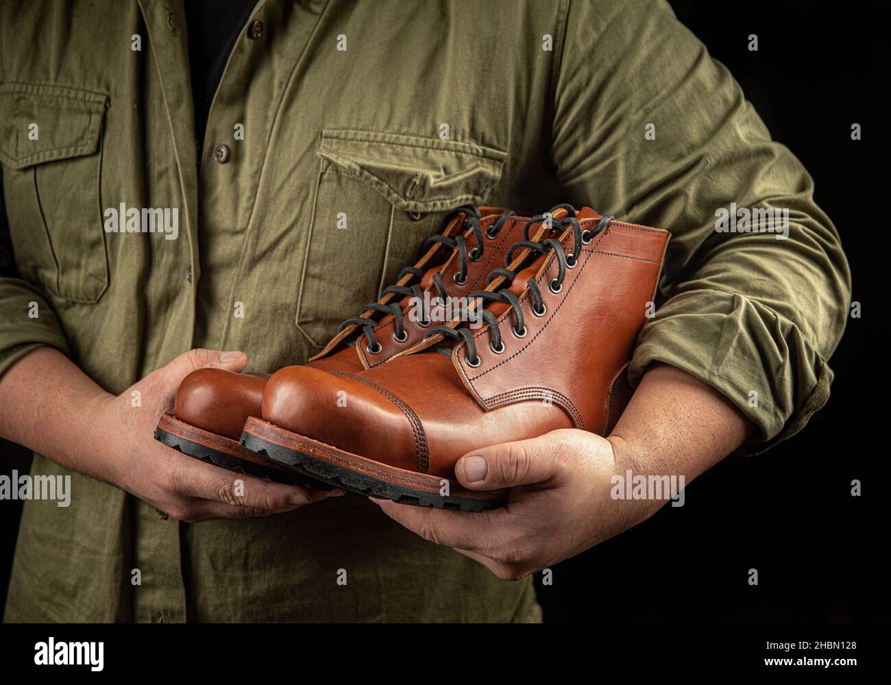 Cobbler che tiene un paio di scarpe in pelle marrone Foto Stock
