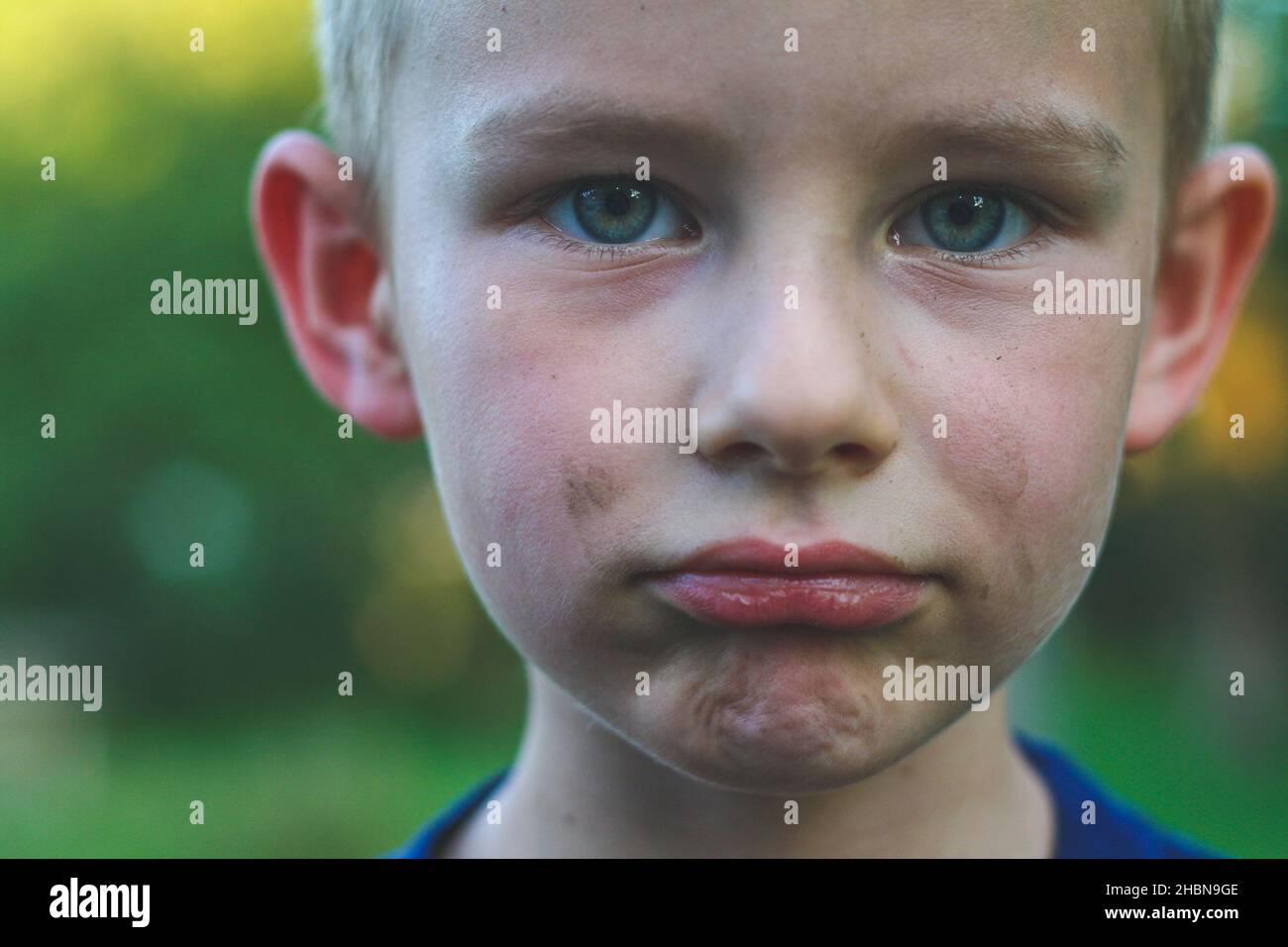 Bambino ragazzo di quattro anni con volto sporco guardare dritto la fotocamera e fare triste volto Foto Stock