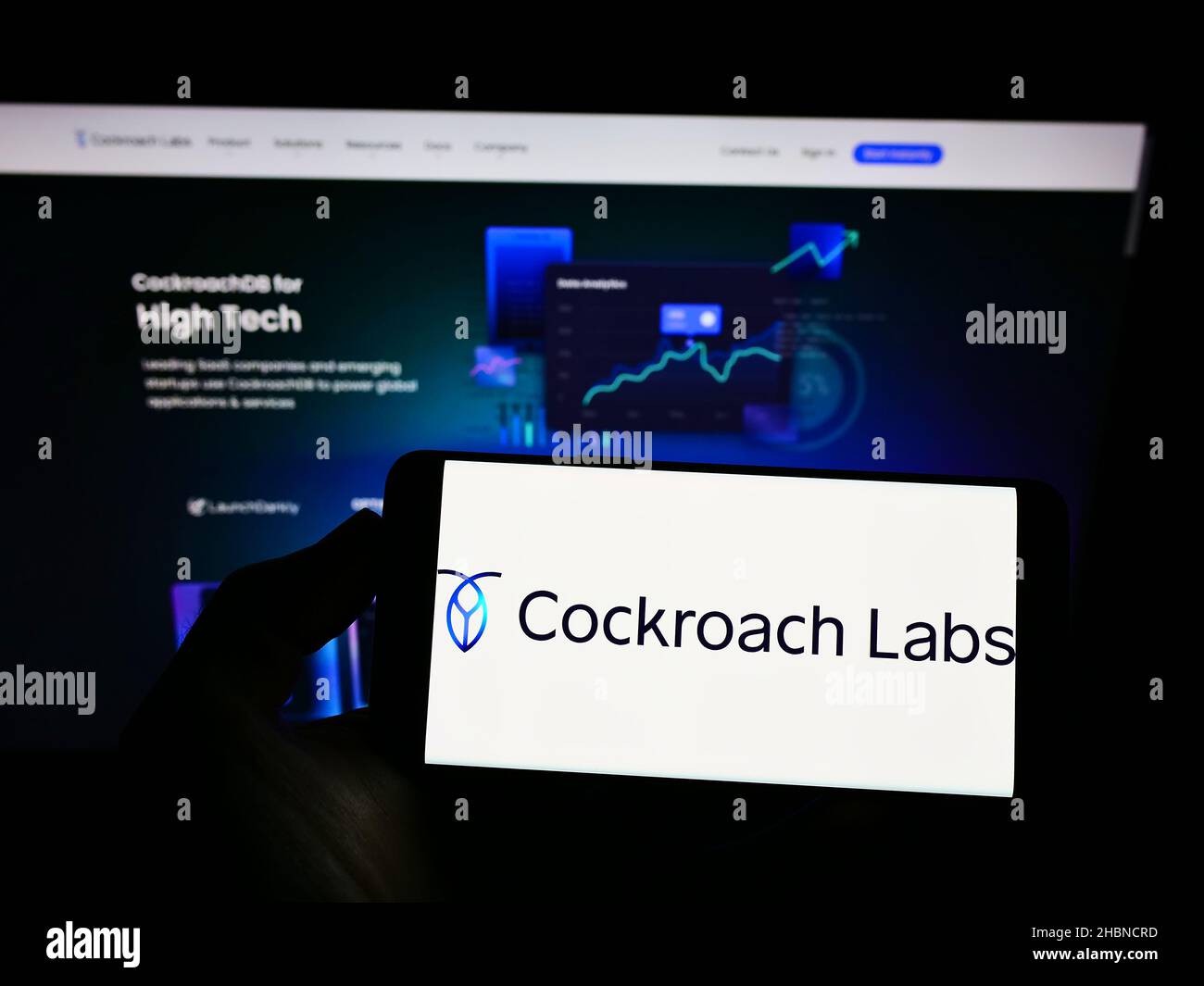 Persona che tiene smartphone con il logo della società di database US SQL Cockroach Labs Inc. Sullo schermo di fronte al sito web. Mettere a fuoco sul display del telefono. Foto Stock