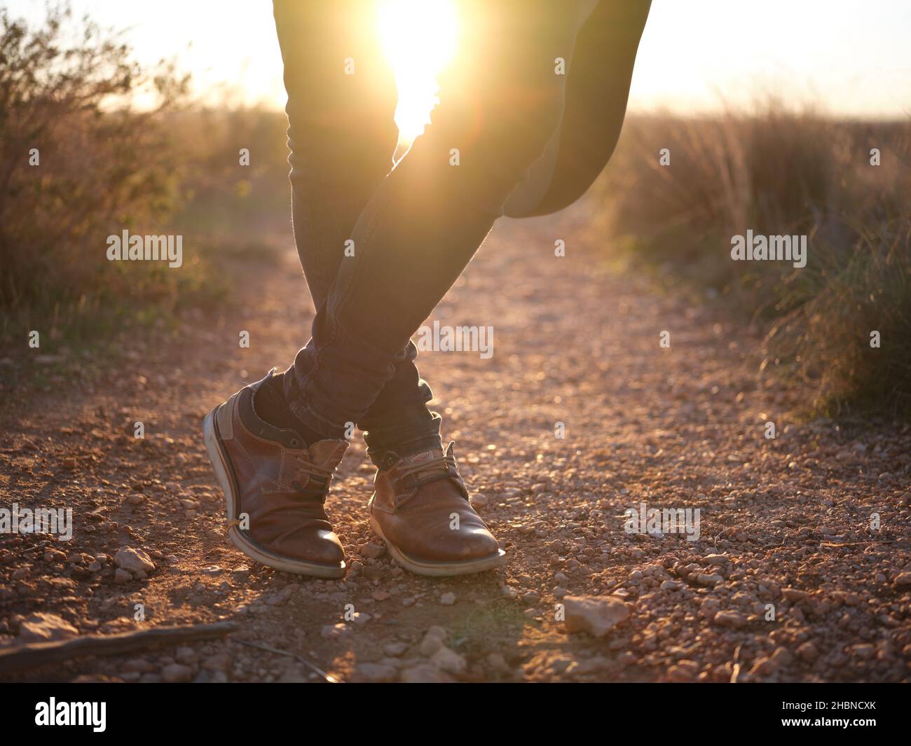le gambe della persona attraversate con il sole che le attraversa al tramonto nella natura Foto Stock