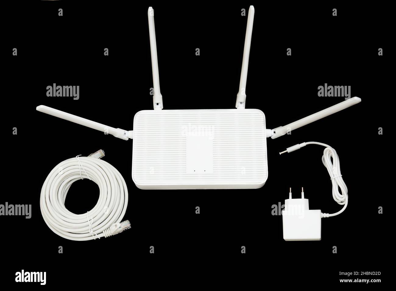 Moderno router Wi-Fi 6 con un adattatore di alimentazione e un rotolo di cavo ethernet isolato su nero. Foto Stock