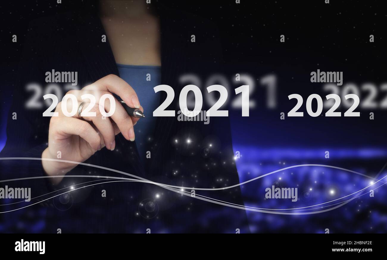 Concept inizio nuovo anno 2022. Penna grafica digitale e disegno ologramma digitale 2021sign su sfondo sfocato scuro della città. Successo nel nuovo anno Foto Stock