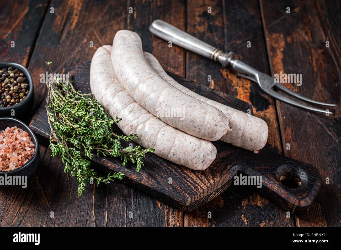 Salsicce bianche tradizionali di Monaco su tavola di legno con timo. Sfondo di legno scuro. Vista dall'alto Foto Stock