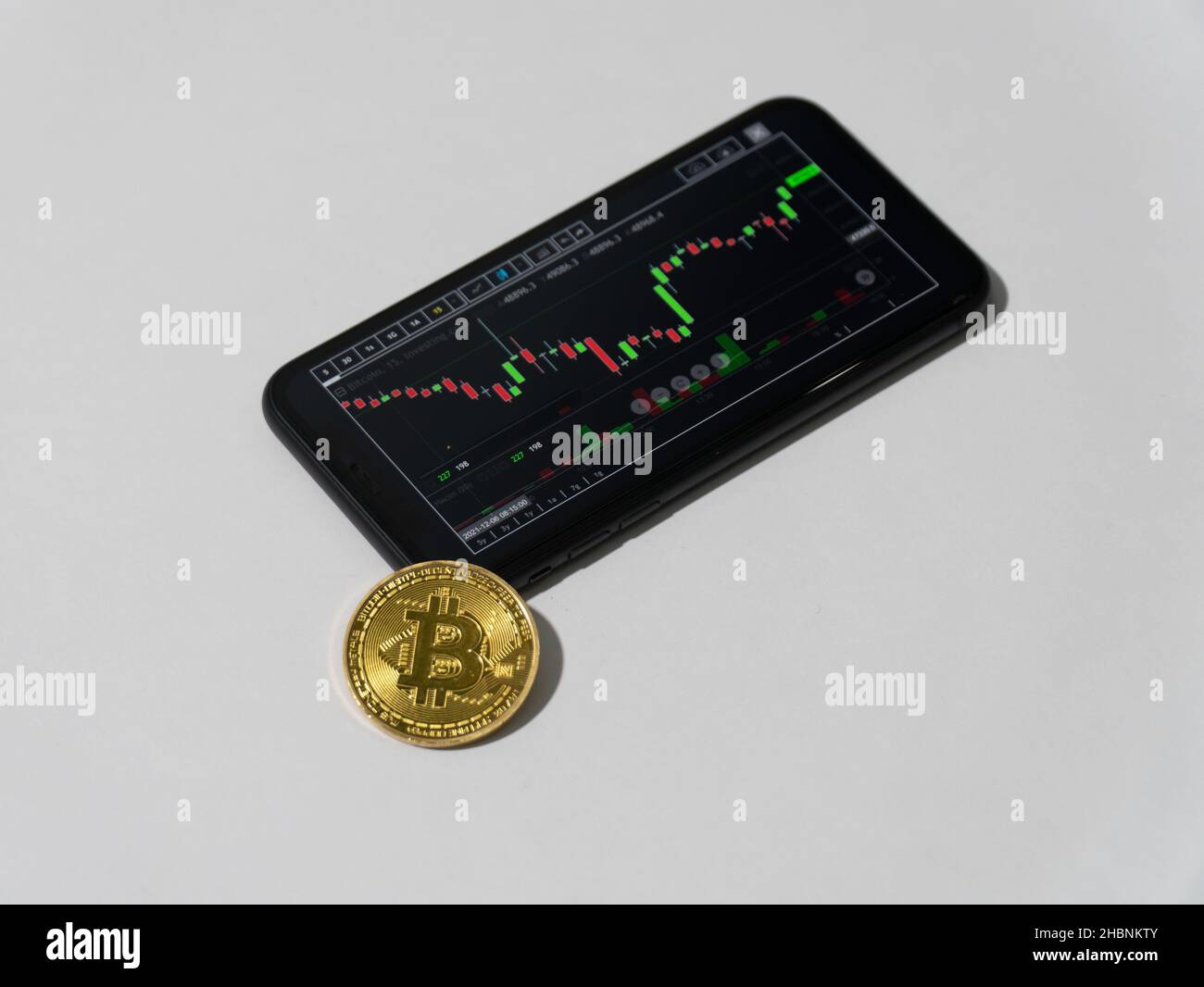 Schermo Bitcoin trader in smartphone con moneta Bitcoin simbolica su sfondo bianco primo piano foto Foto Stock