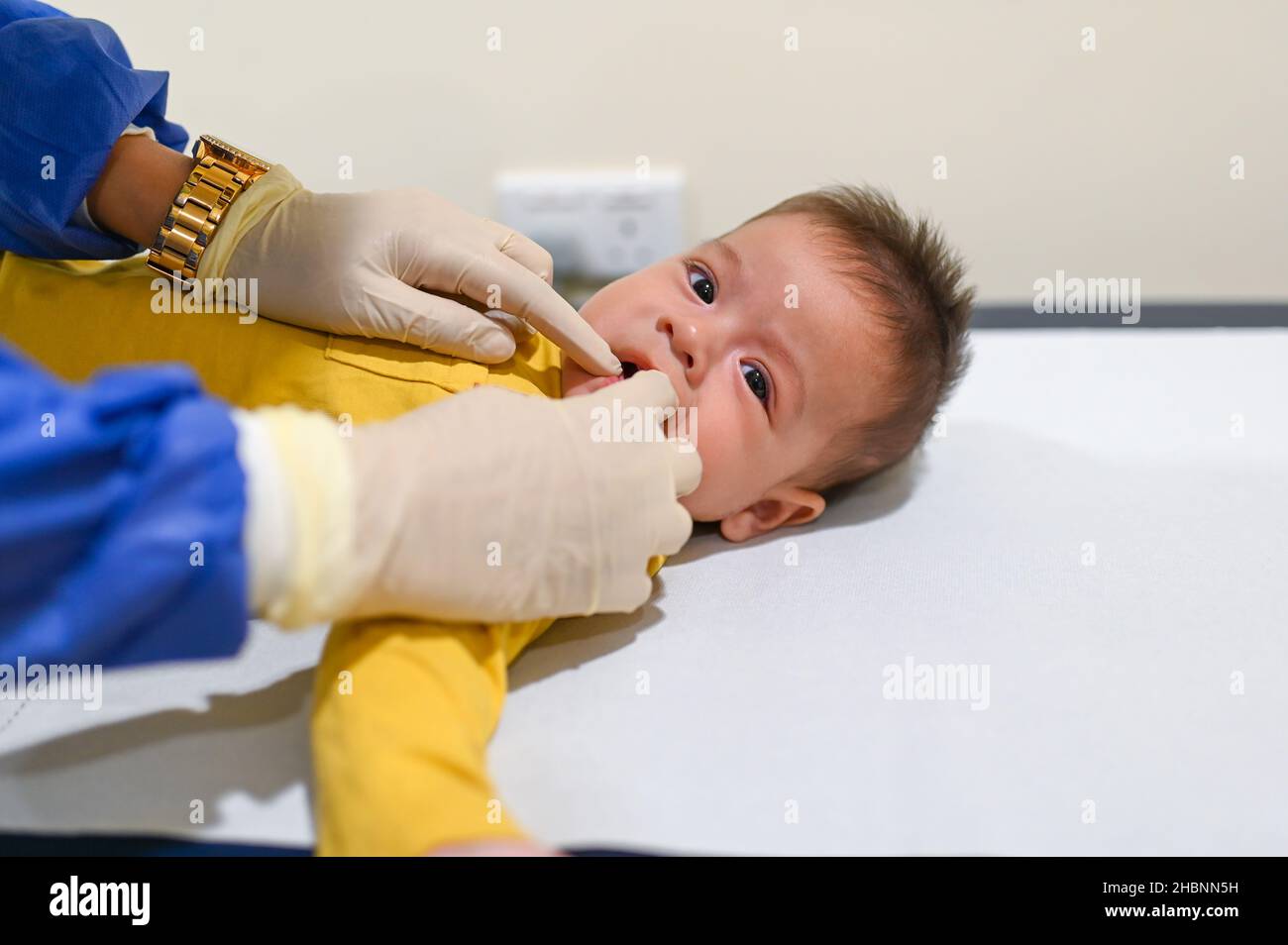 Dottore controllo denti e teething processo di un bambino di razza mista di 5 mesi presso l'ufficio medici per un controllo di routine e l'esame fisico per trac Foto Stock