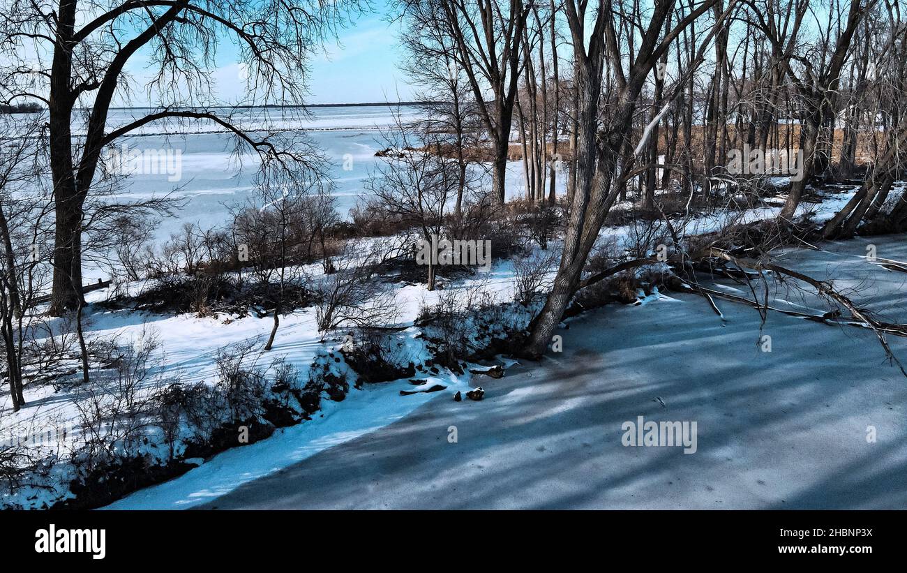 Vista sul lago di Winneconne ghiacciato da dietro una piccola isola di alberi. Un tocco sbiadito aggiunto per un'atmosfera rilassante. Neve fresca caduta sbarcati giorno prima. Foto Stock