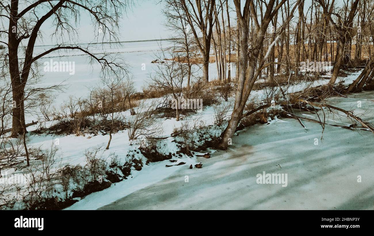 Vista sul lago di Winneconne ghiacciato da dietro una piccola isola di alberi. Un tocco sbiadito aggiunto per un'atmosfera rilassante. Neve fresca caduta sbarcati giorno prima. Foto Stock