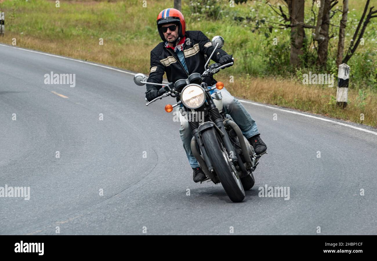 Uomo che guida la sua moto classica al parco nazionale Khao Yai Foto Stock