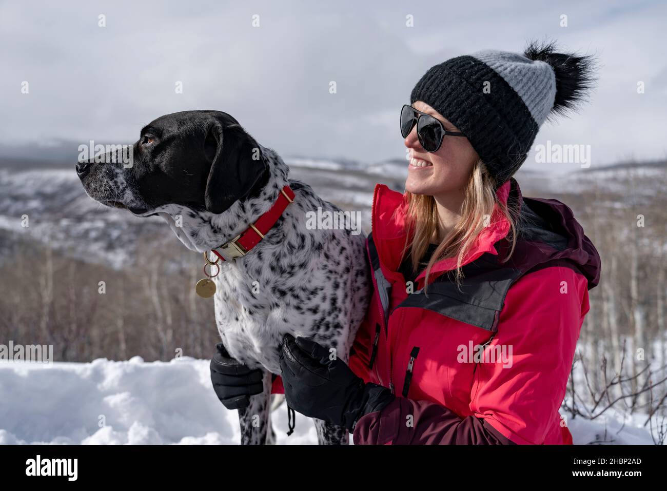 Donna sorridente escursioni con il cane durante le vacanze invernali Foto Stock