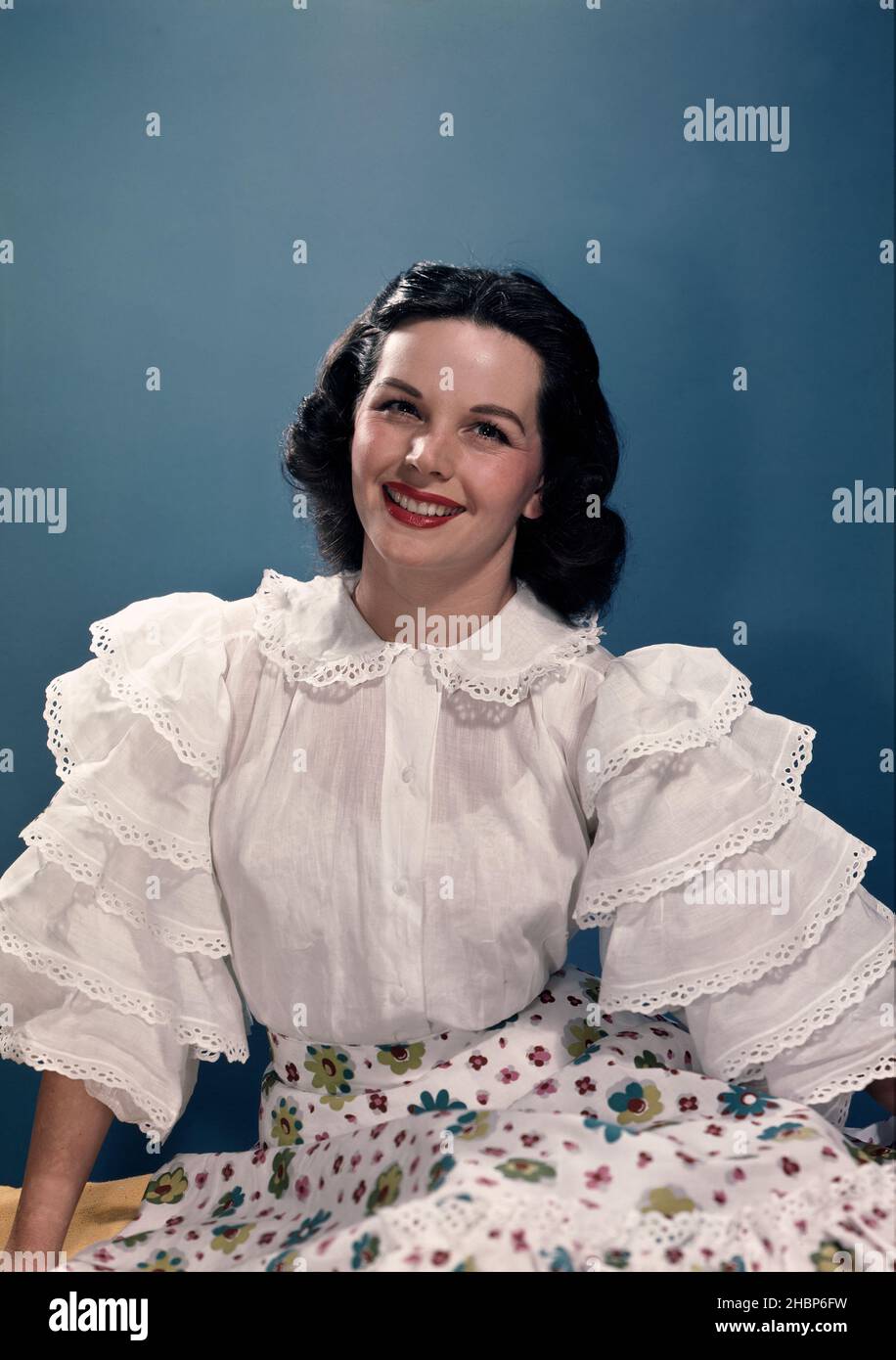 Giovane donna ritratto con blusa bianca e abito stampa fiore su sfondo blu Foto Stock