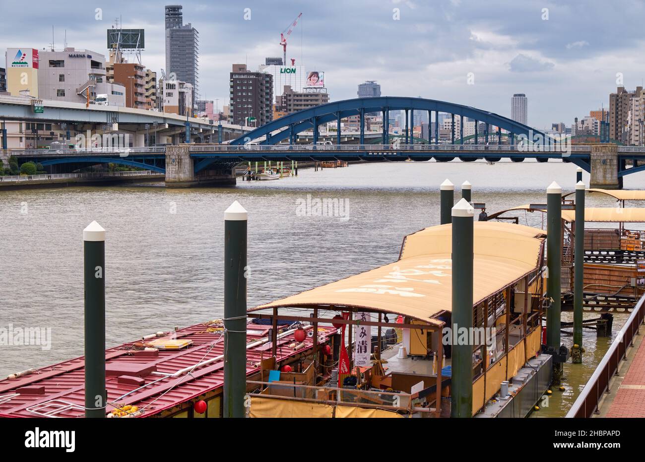 Tokyo, Giappone - 24 ottobre 2019 Houseboat (YAKATABUNE) per la crociera sul fiume Sumida e ponte blu Komagata ad arco legato che collega Koma Foto Stock