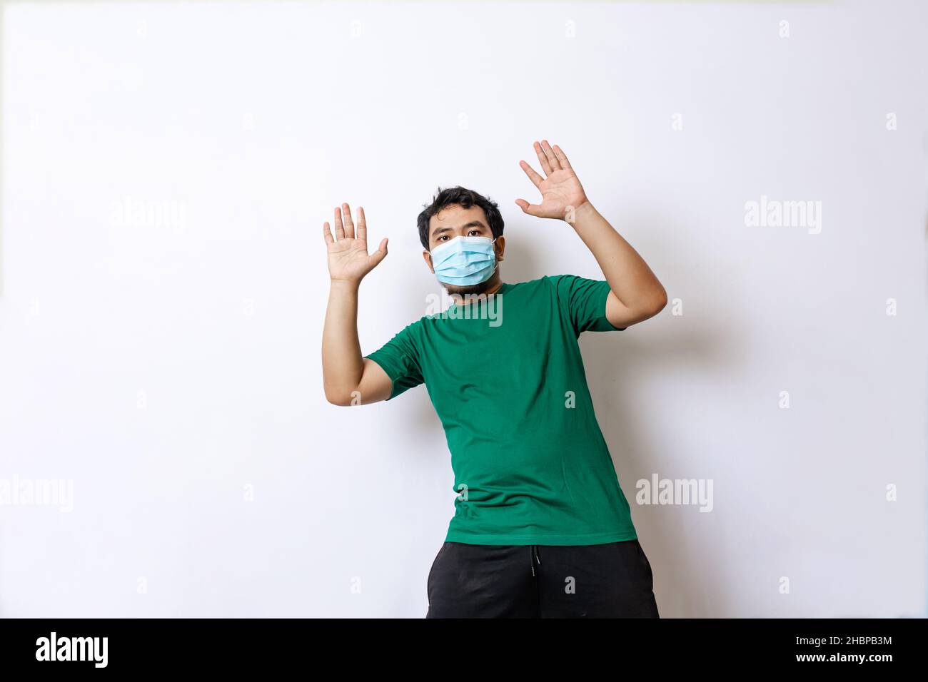 uomo asiatico in camicia verde con maschera in posa casuale Foto Stock