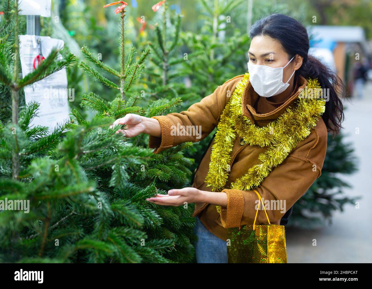Donna in maschera protettiva che passa il tempo alla fiera e l'acquisto di decorazioni di Natale Foto Stock