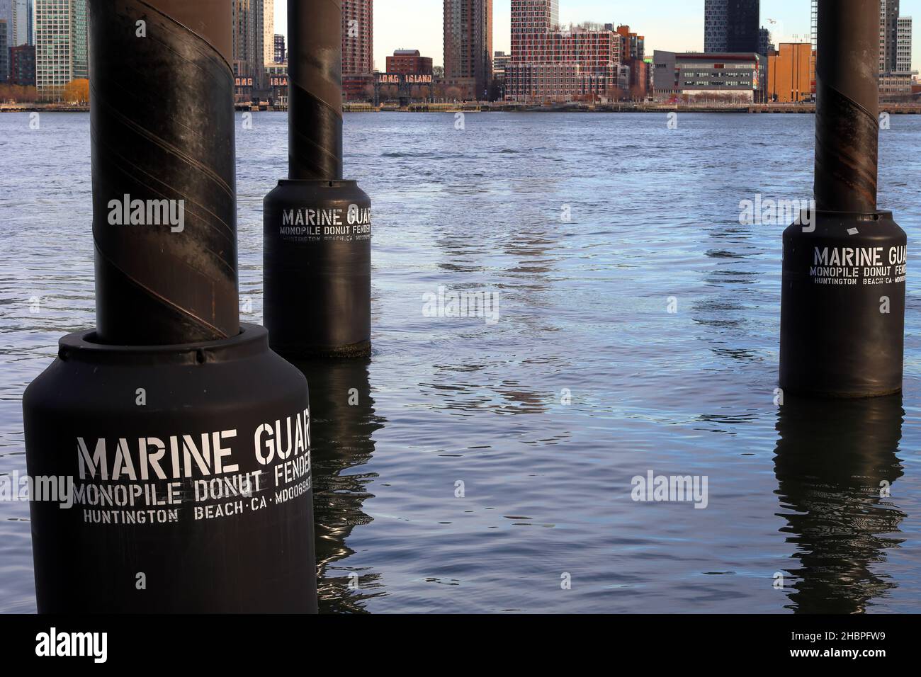 Marine Guard Monopile parabordi galleggianti nel fiume East River, New York. I parabordi galleggianti in stile ciambella proteggono le navi dallo schiantarsi in monopile marino Foto Stock