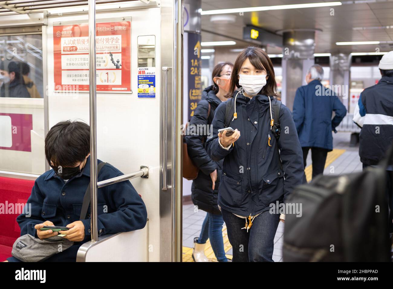 Pendolari in metropolitana con smartphone, una donna che indossa maschere entrando in auto. Restrizioni del Covid-19. Foto Stock