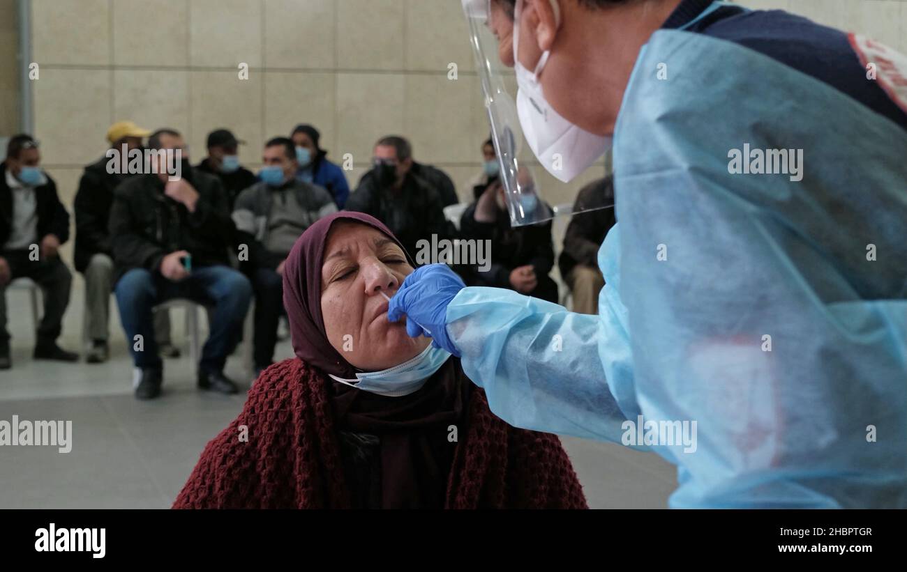 Erez Crossing, Israele. 2nd Dic 2021. Una paramedica del Magen David Adom, il servizio medico di emergenza nazionale di Israele, raccoglie un campione di tampone da una donna palestinese, prima di entrare in Israele dalla striscia di Gaza, in una stazione mobile di test COVID-19 al confine Gaza-Israele il 20 dicembre 2021 al valico di Erez, Israele. Israele ha vietato viaggi da e per diversi paesi a causa della variante COVID-19 Omnicron. Gli israeliani che tornano nel paese devono essere messi in quarantena indipendentemente dallo stato di vaccinazione. Credit: Eddie Gerald/Alamy Live News Foto Stock