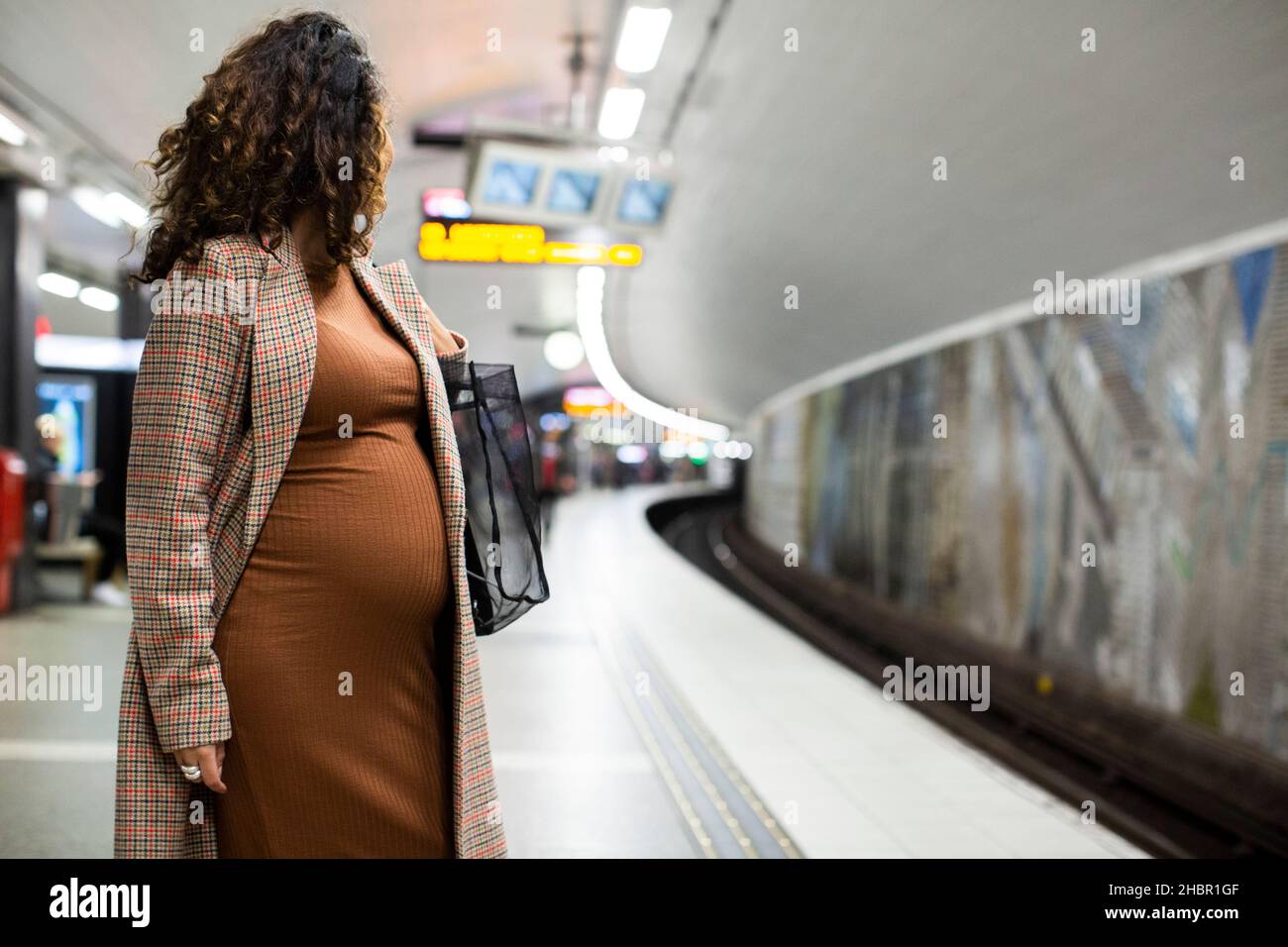 Donna d'affari incinta in attesa di treno alla piattaforma Foto Stock