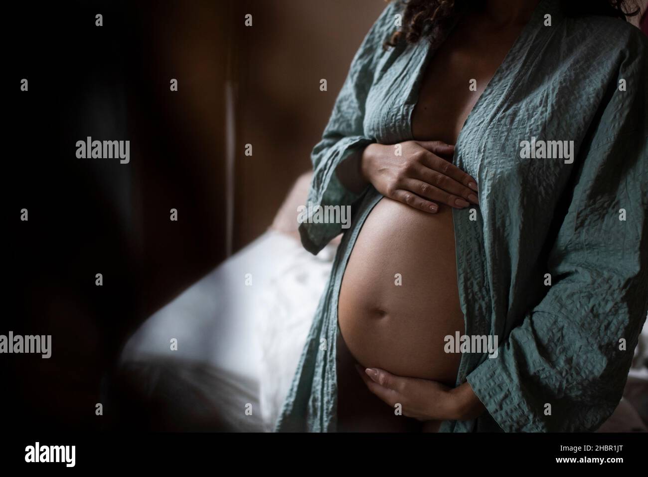 Sezione mediana della donna incinta toccando ventre a casa Foto Stock