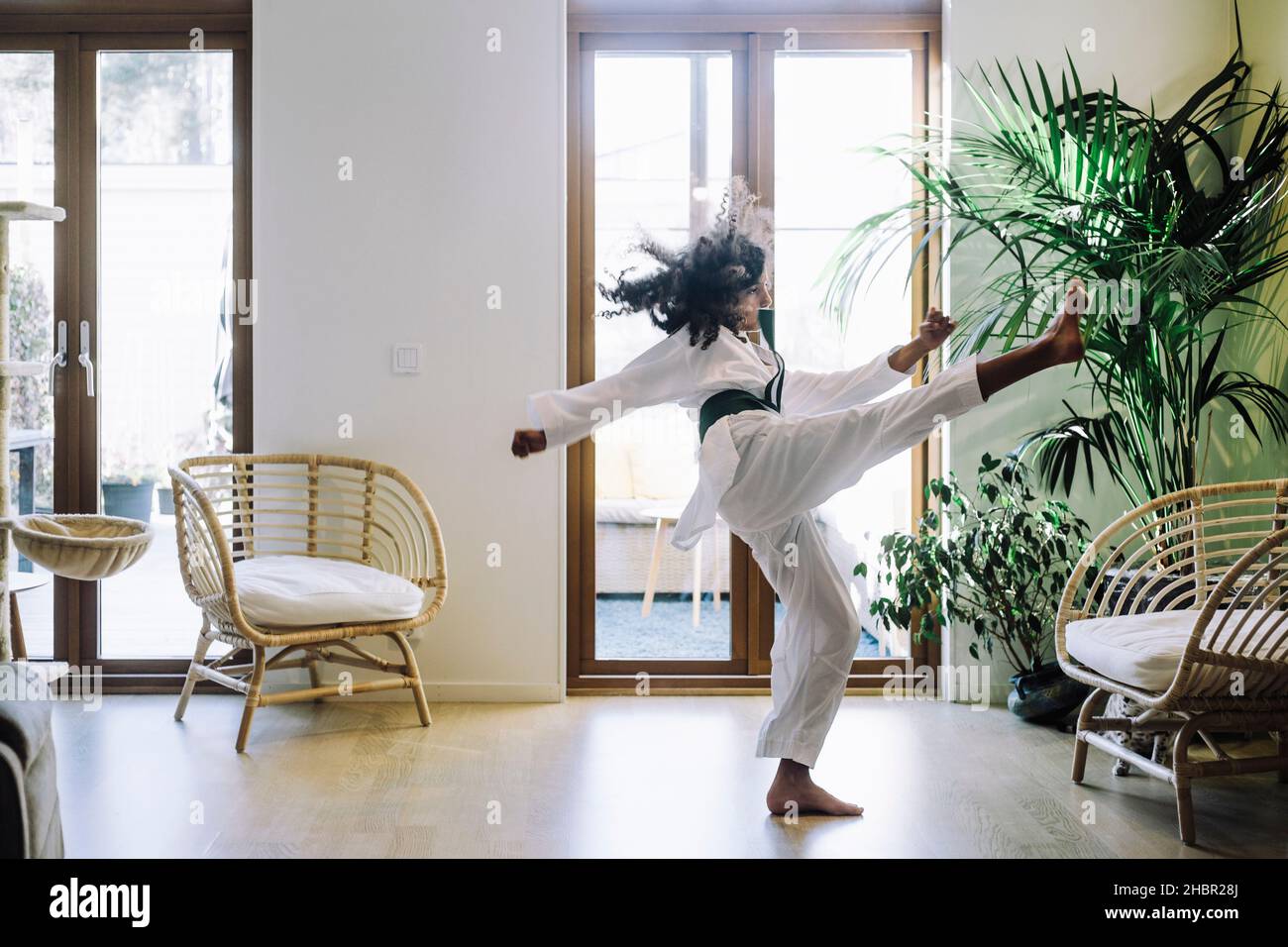 Ragazza ambiziosa che pratica il karate in soggiorno Foto Stock