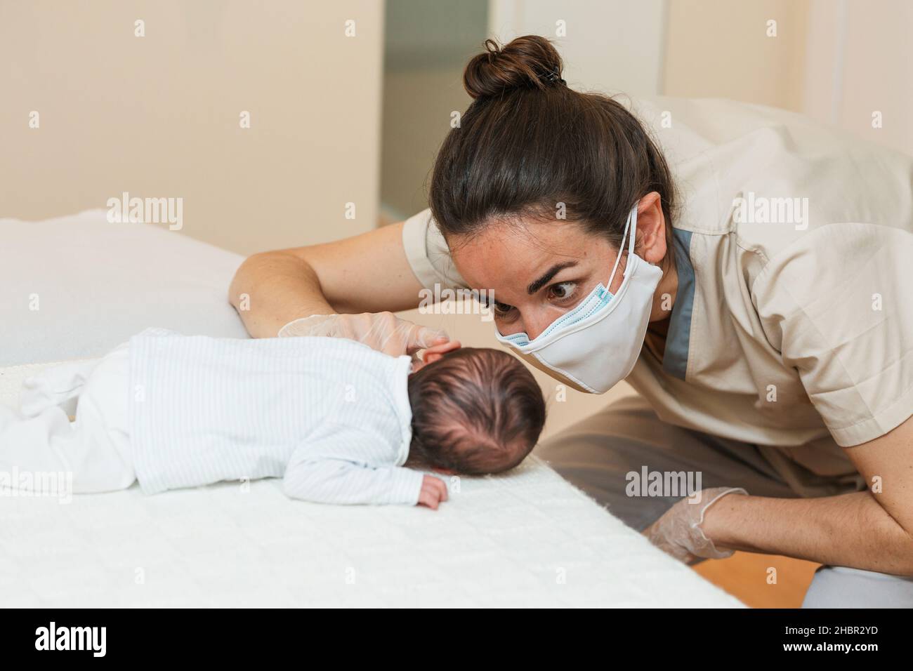 Fisioterapista che effettua la stimolazione muscolare pro-decubito su un neonato. Foto Stock