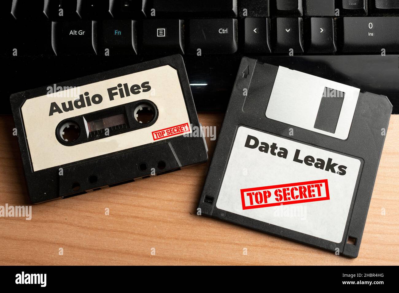Concetto di perdita di dati: Cassetta audio e floppy disk con dati top secret su un tavolo di legno Foto Stock