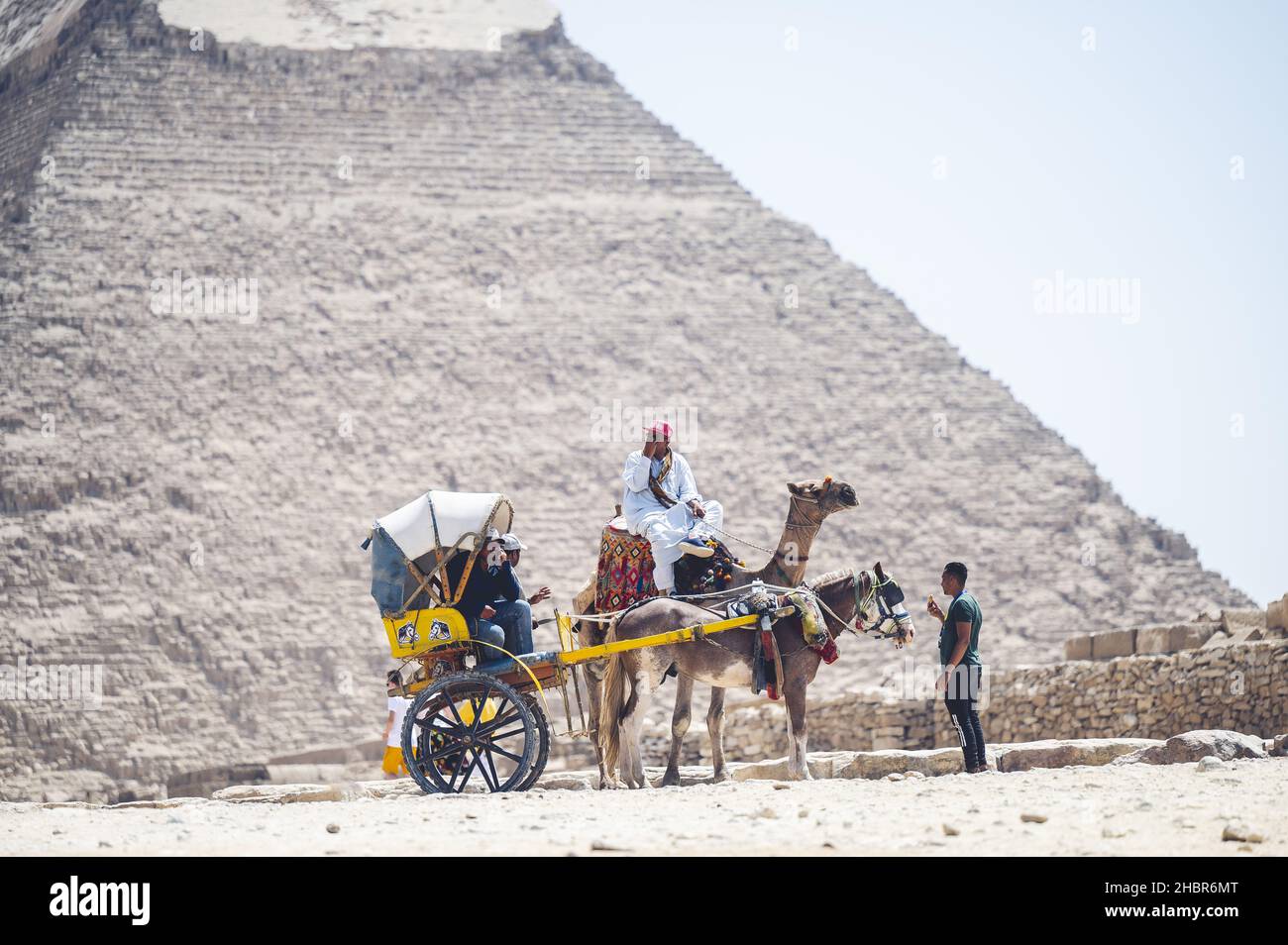 CAIRO, EGITTO - 04 giu 2021: Le grandi piramidi e la gente che cavalcano cammelli, Cairo, Egitto Foto Stock