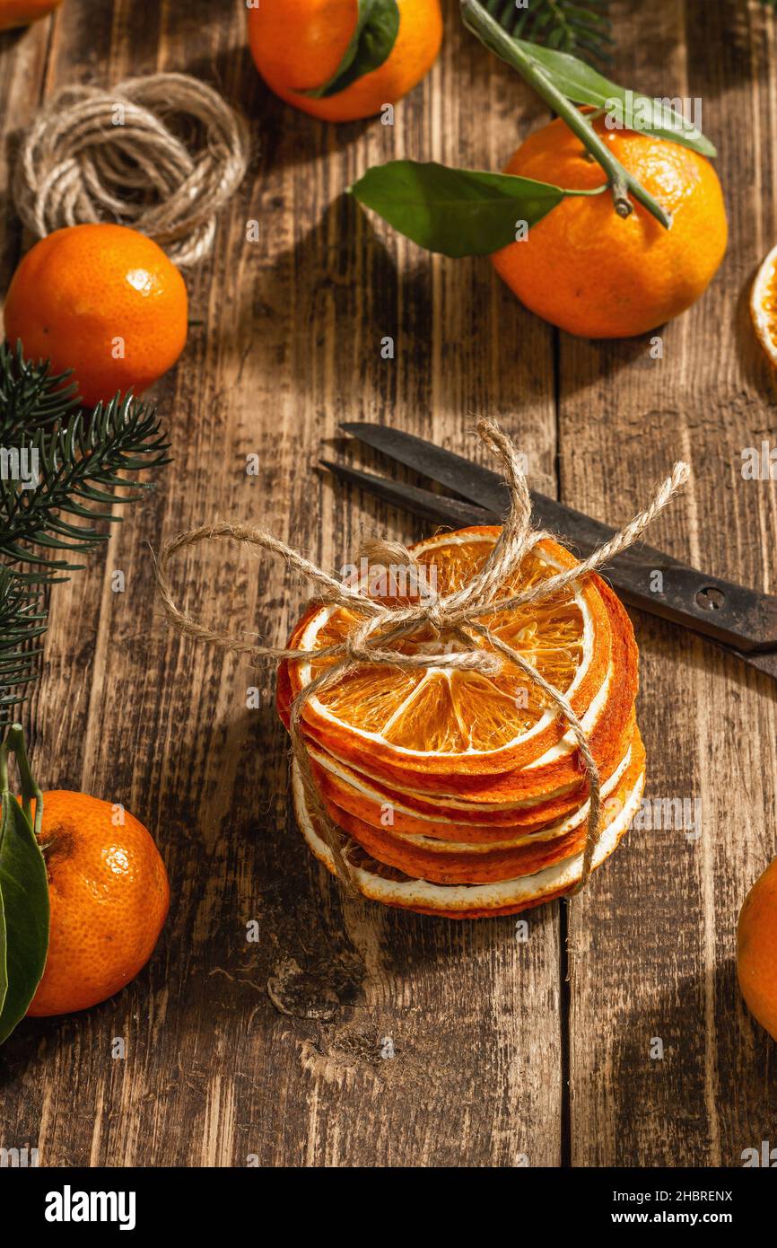 Snack a fette di arance secche. Agrumi secchi per decorazioni natalizie.  Tangerini con foglie, rami di abete, forbici e filo. Supporto in legno Foto  stock - Alamy
