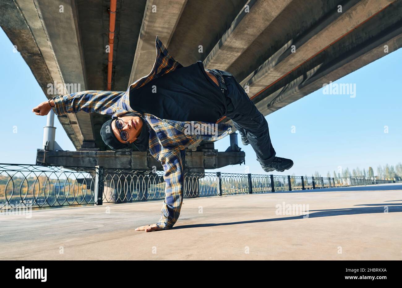 Il giovane uomo si rompe ballando su sfondo urbano con acrobazie acrobatiche. L'artista di strada frangidanze all'aperto Foto Stock