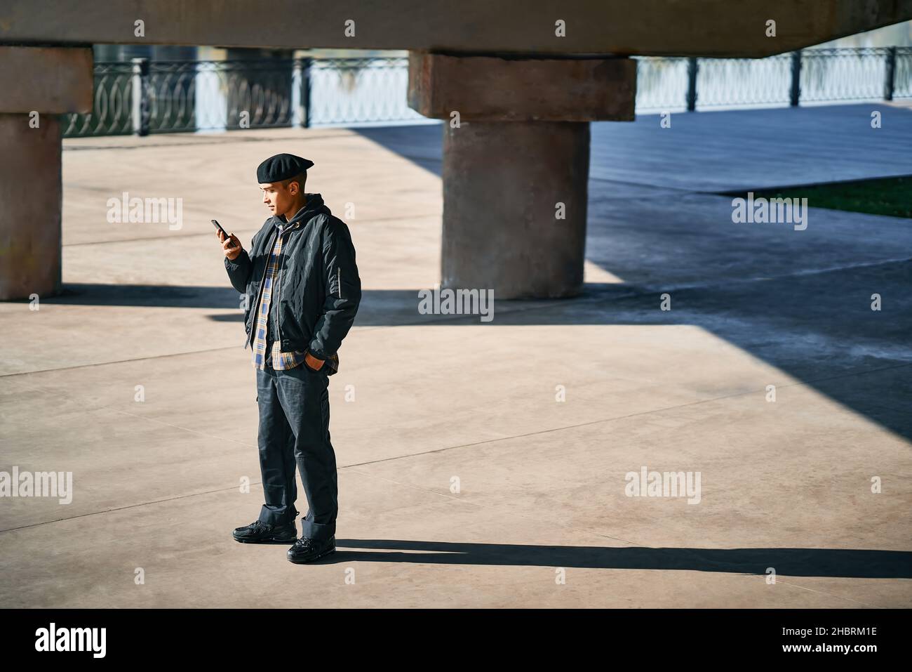 Uomo di hipster millenario che utilizza lo smartphone su sfondo urbano con spazio di copia Foto Stock