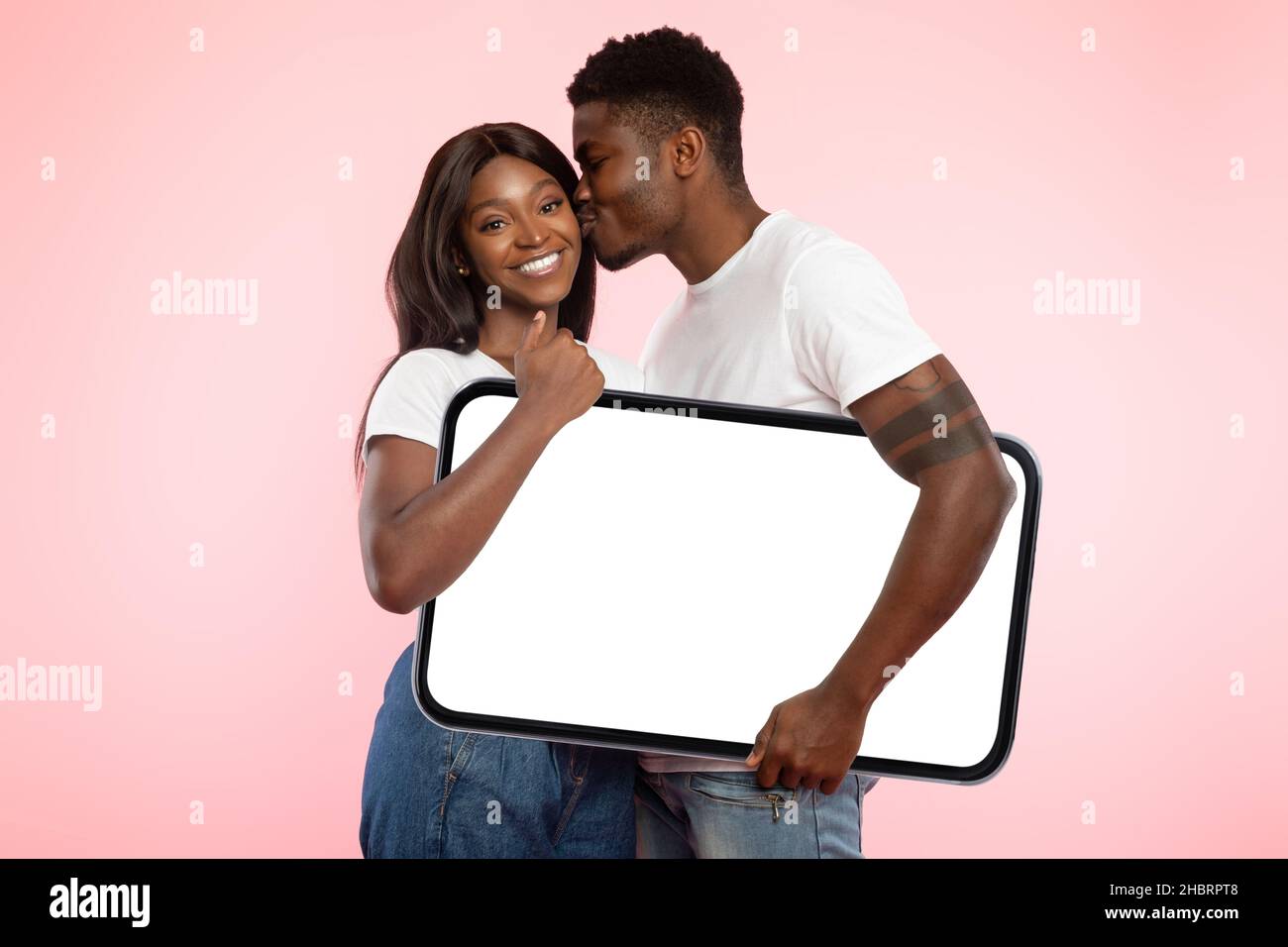 Coppia nera che tiene bianco bianco schermo del telefono e baciare Foto Stock