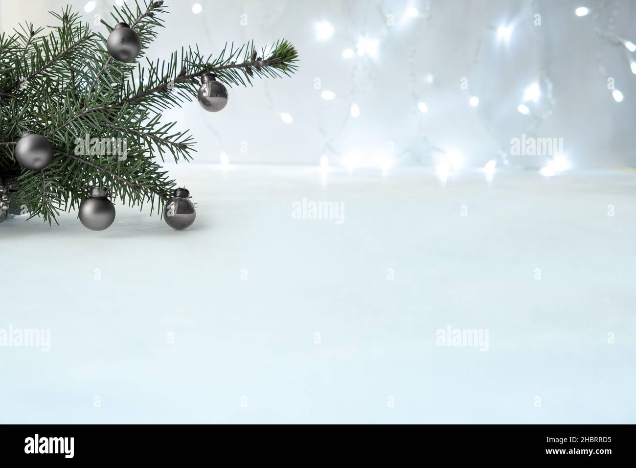 Sfondo di Capodanno e Natale con ghirlande argentate con luci con bokeh in sfocatura. Colori grigi neutri con spazio di copia e simulazione Foto Stock
