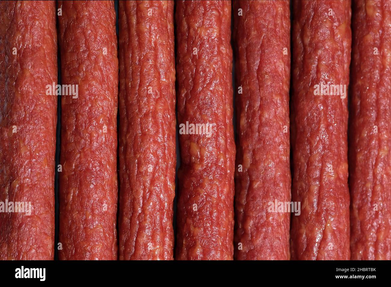 Salsiccia affumicata con vista dall'alto. Caccia salsicce vicino sfondo. Molta salsiccia affumicata. Spuntini da carne a birra. Foto Stock