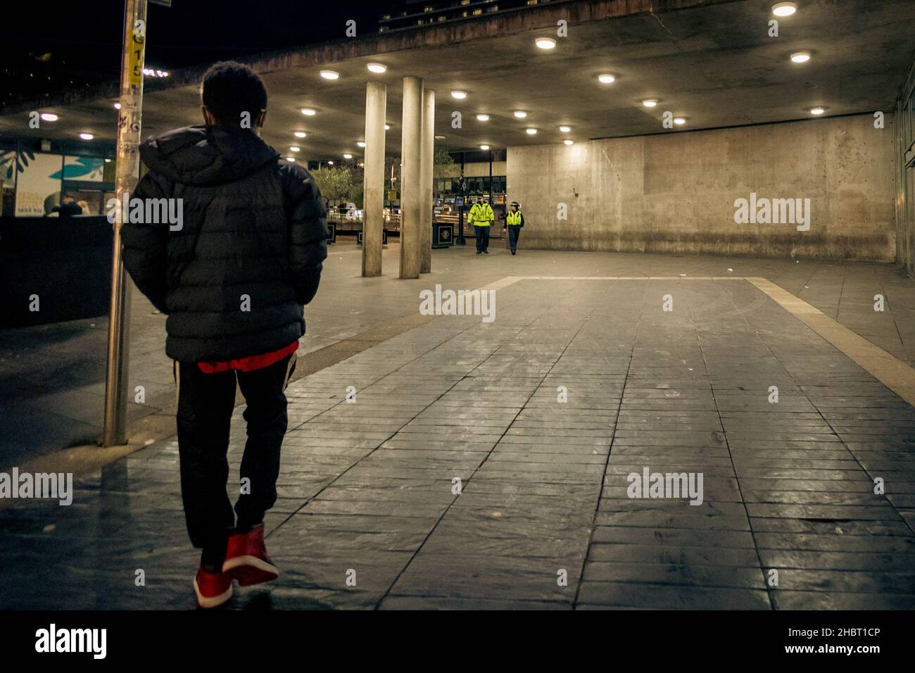 Un ragazzino nero che cammina verso 2 poliziotti di notte Foto Stock