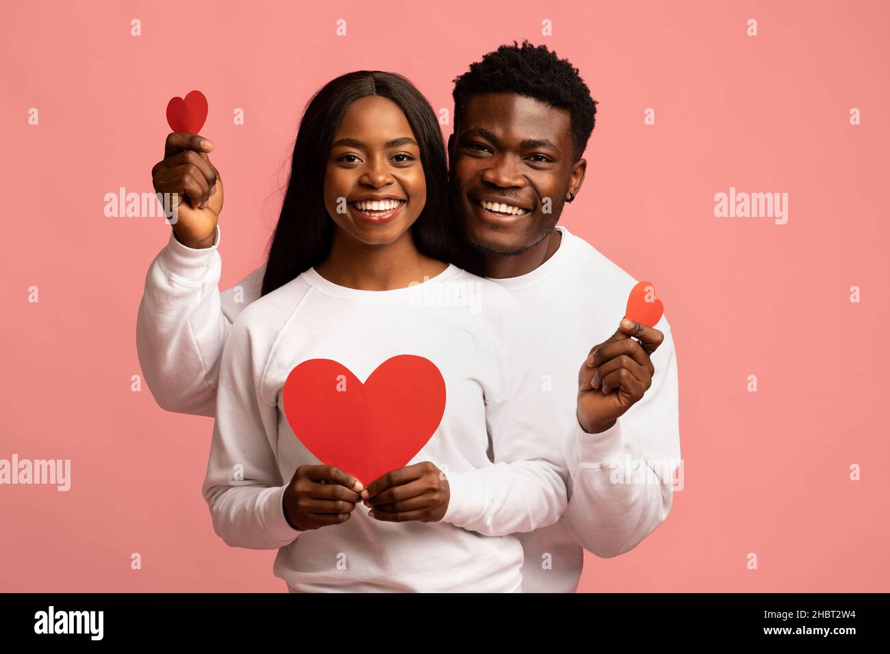 Felici amanti afroamericani in posa con cuori rossi Foto Stock