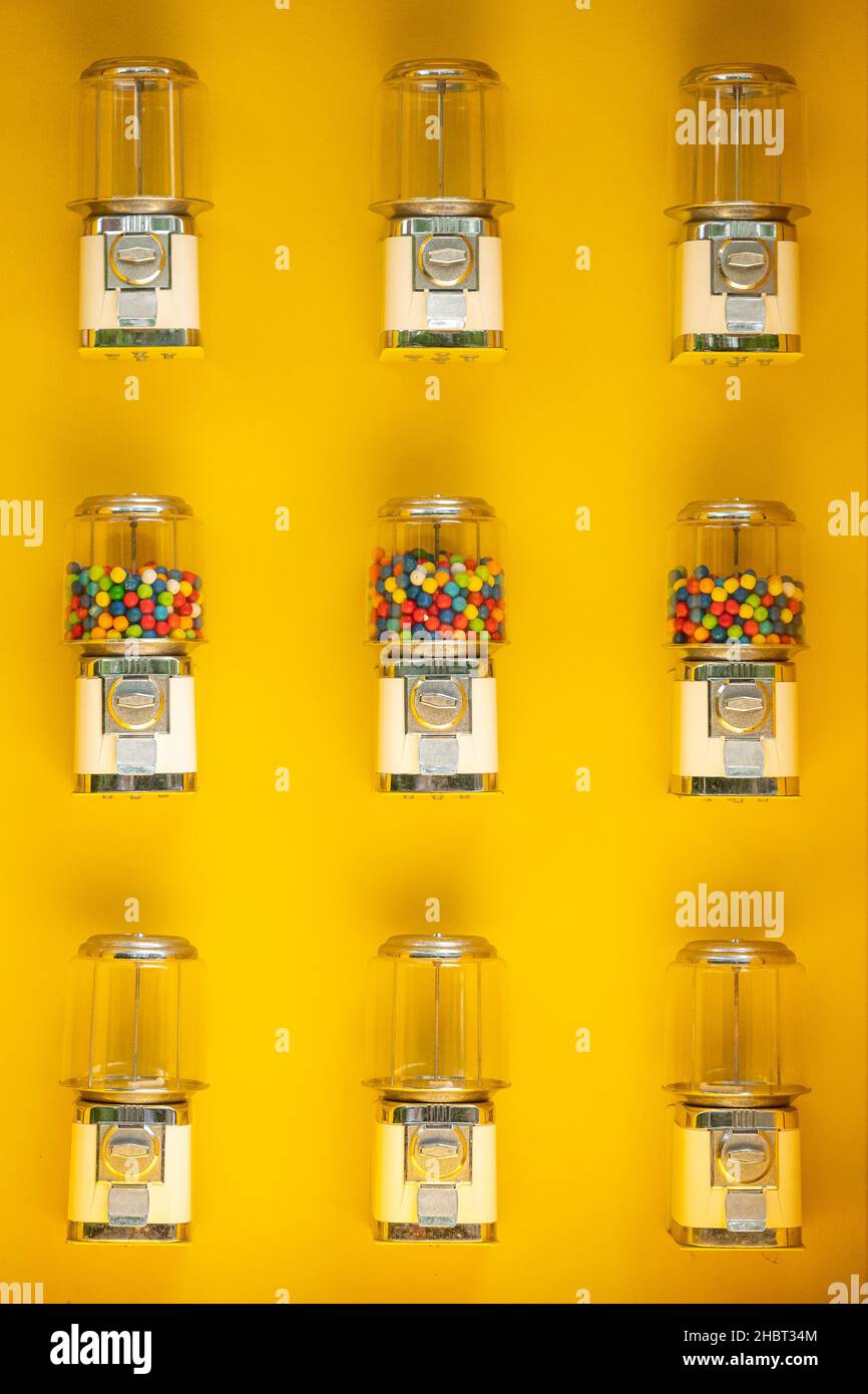 Distributori automatici di gumball contro un muro giallo Foto Stock
