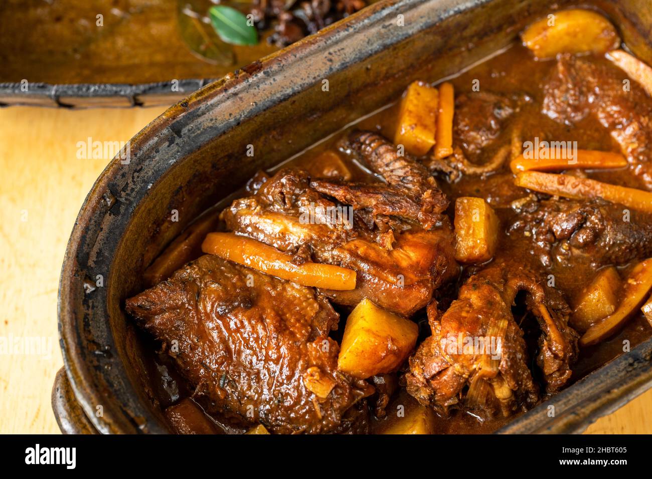 Gallina piccante al forno, tagliata a pezzi con verdure e frutta in una teglia rustica in terracotta, a forno lungo. Vecchia specialità boema, primo piano. Foto Stock