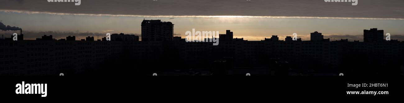 Panorama di una zona residenziale al crepuscolo mattutino sopra di essa un inusuale skyline attraverso il quale il sole splende (St Petersburg, Russia) Foto Stock
