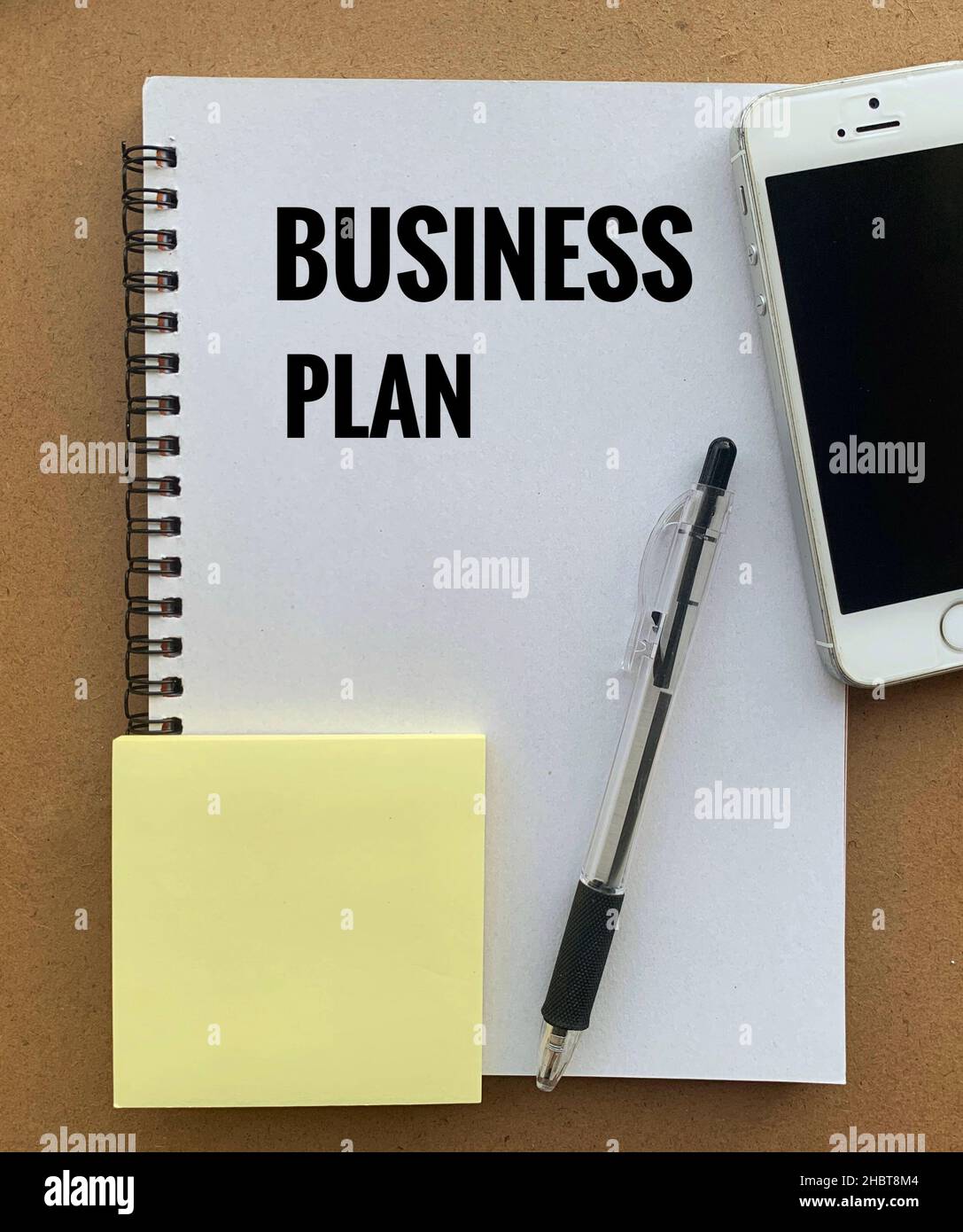 Testo del piano aziendale su appunti con smartphone, penna e sfondo adesivo. Foto Stock