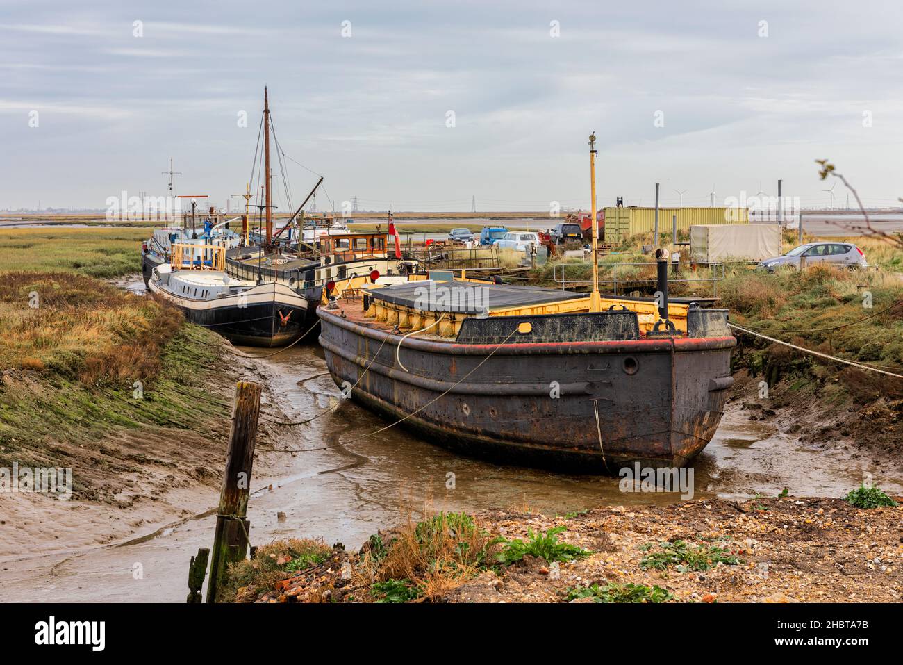 Chiatte e barche fondate a Low Tide sul fiume Medway Estuary a Upchurch in Kent, Inghilterra Foto Stock