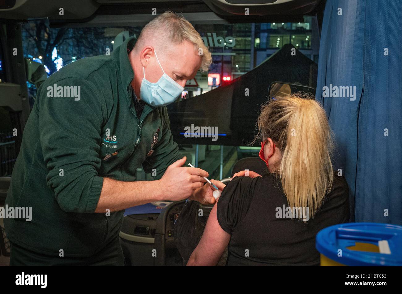 Bryan Finlay somministra un'iniezione di richiamo sul bus di vaccinazione mobile NHS Scotland nel centro di Edimburgo, in quanto il programma di vaccinazione di richiamo del coronavirus è aumentato fino a un ritmo di consegna senza precedenti, A ogni adulto idoneo in Scozia viene offerta una iniezione di rabbocco entro la fine di dicembre. Data foto: Martedì 21 dicembre 2021. Foto Stock