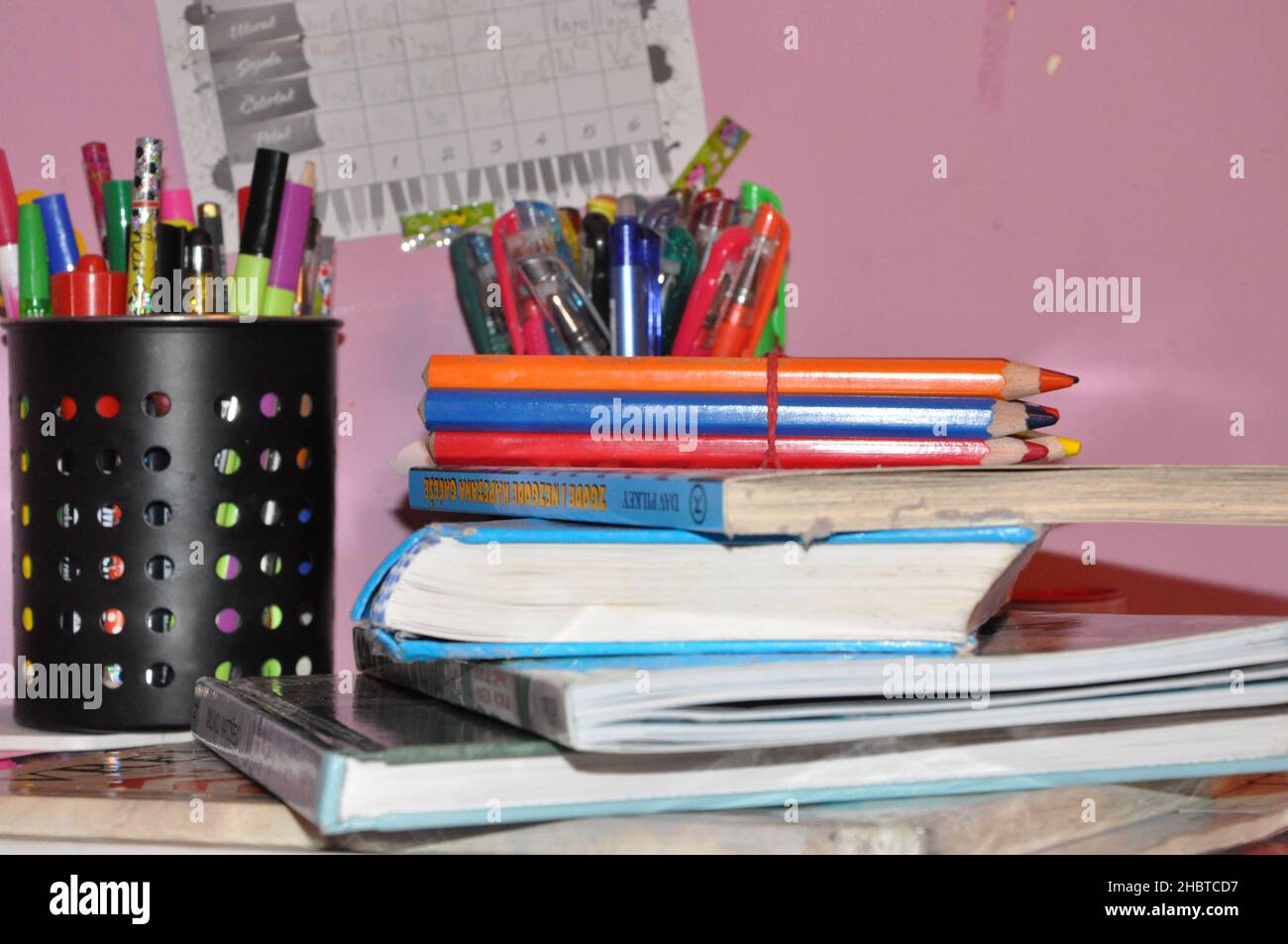 Un mucchio di libri e articoli di cancelleria su uno sfondo di lavagna. Scrivania, istruzione, scuola. Foto Stock